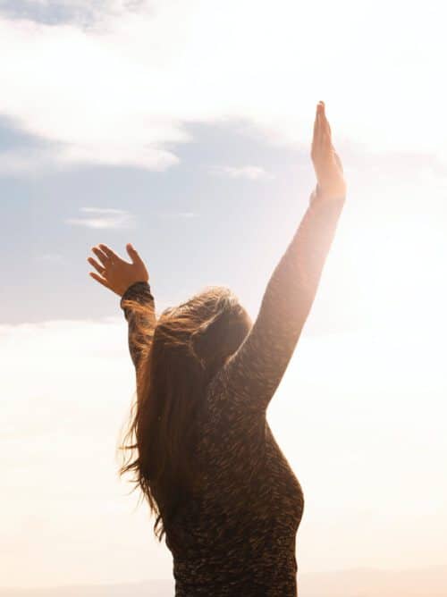 Frau mit ausgebreiteten Armen steht in der Morgensonne, symbolisiert Freiheit, Kraft und spirituelle Lebensberatung der bioenergetischen Naturheilpraxis in Hürth
